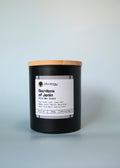 Black candle with a wooden lid and white label on a light gray background