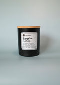 Black container with a wooden lid labeled 'Orange Tea of Yaffa' on a light gray background